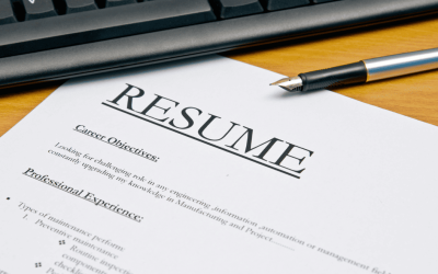 A resume sitting under a pen and a computer keyboard