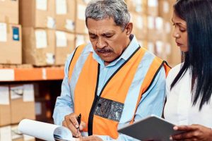 A supply chain manager and a warehouse superviser reviewing inventory